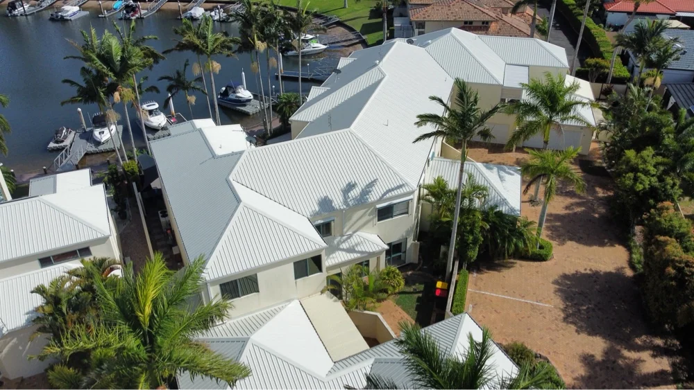 Aerial view of light-coloured roofs beside a waterfront