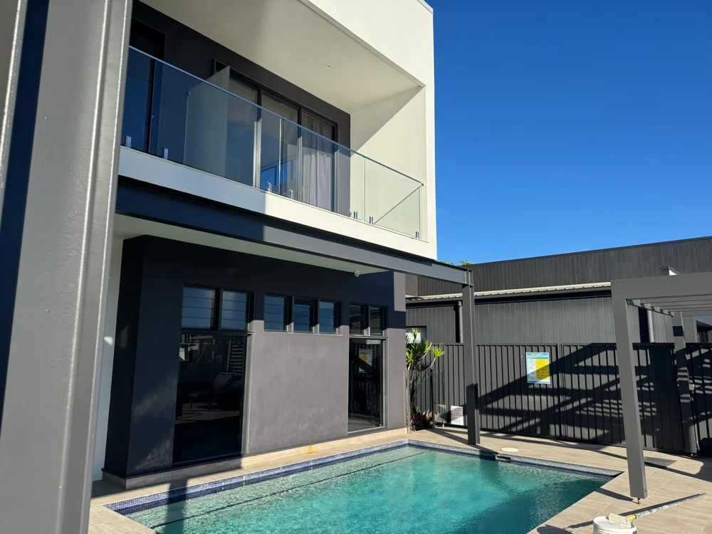 White upper storey and charcoal exterior beside a pool